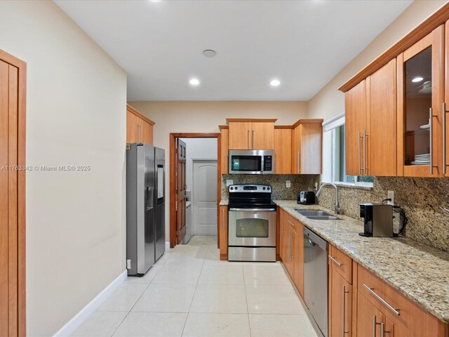 9457 Carlyle Ave, Surfside, FL 33154 - kitchen with stainless steel appliances, tasteful backsplash, light stone counters, glass insert cabinets, and light tile patterned flooring