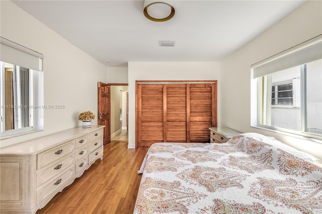 bedroom featuring light wood-style floors, visible vents, baseboards, and a closet