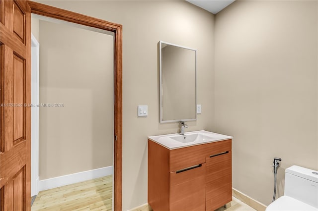 bathroom with toilet, baseboards, wood finished floors, and vanity