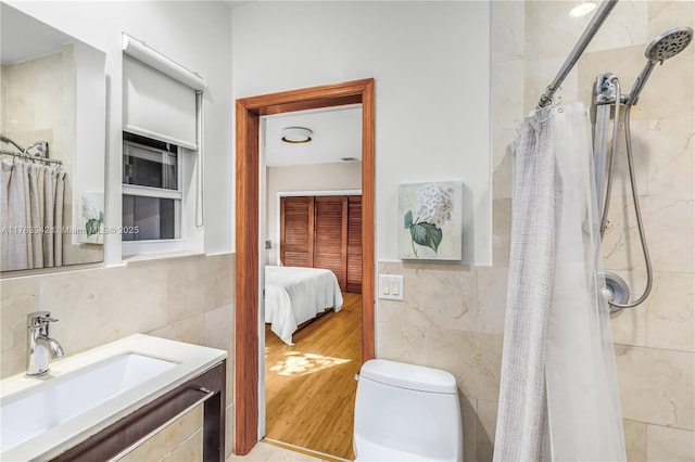 full bathroom with tile walls, toilet, curtained shower, and wood finished floors