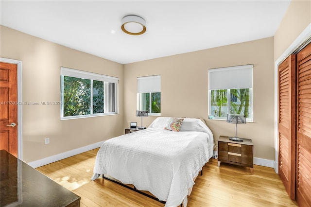 bedroom with baseboards, light wood finished floors, and multiple windows