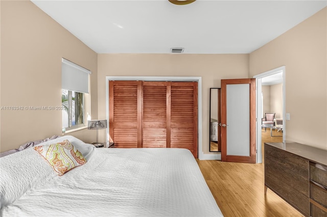 bedroom with baseboards, visible vents, light wood finished floors, and a closet