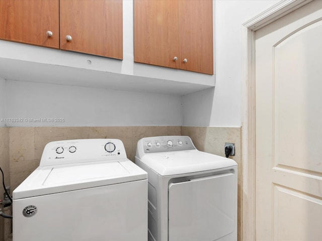 laundry area featuring cabinet space, washer and dryer, and tile walls