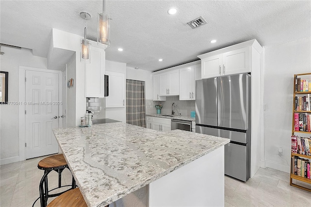 kitchen with light stone countertops, a peninsula, white cabinets, stainless steel appliances, and baseboards