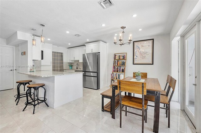 8 Hathaway Ln, Wilton Manors, FL 33305 - kitchen featuring freestanding refrigerator, a peninsula, light stone counters, white cabinetry, and a breakfast bar area