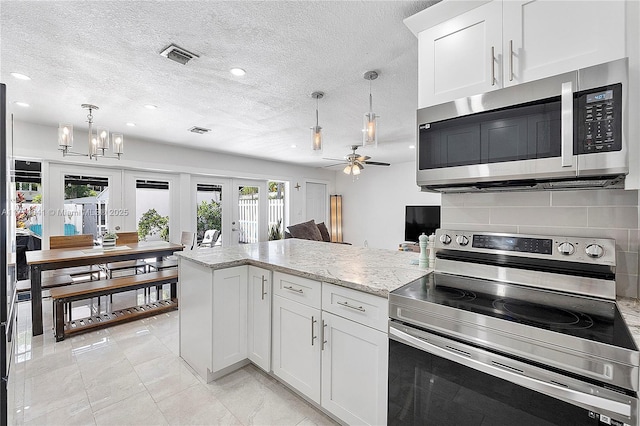 kitchen featuring visible vents, a peninsula, ceiling fan with notable chandelier, french doors, and stainless steel appliances