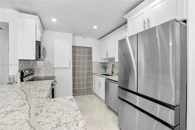 8 Hathaway Ln, Wilton Manors, FL 33305 - kitchen featuring appliances with stainless steel finishes, a sink, light stone countertops, white cabinets, and recessed lighting