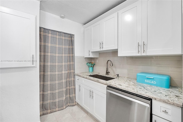 kitchen featuring a sink, stainless steel dishwasher, white cabinets, and light stone countertops