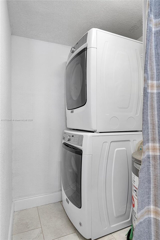 8 Hathaway Ln, Wilton Manors, FL 33305 - laundry area featuring stacked washer / dryer, baseboards, a textured ceiling, and light tile patterned floors