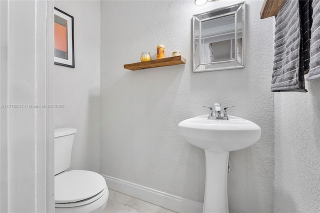 bathroom with toilet, tile patterned flooring, and baseboards