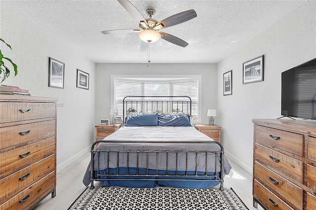 bedroom with baseboards, a ceiling fan, a textured wall, and a textured ceiling