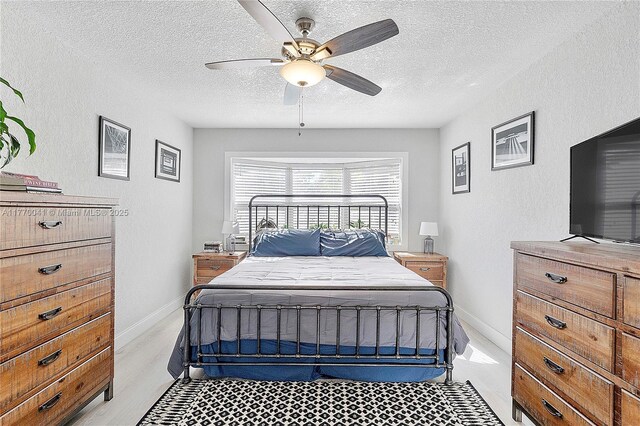8 Hathaway Ln, Wilton Manors, FL 33305 - bedroom featuring a textured ceiling, a textured wall, a ceiling fan, light wood-style flooring, and baseboards