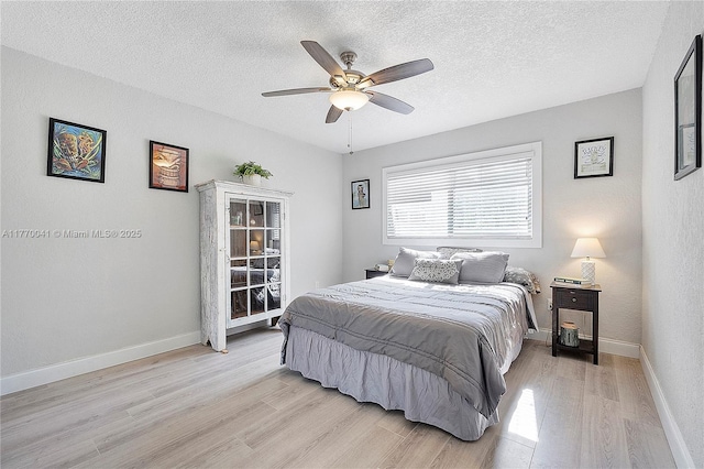 bedroom featuring light wood-style floors, ceiling fan, baseboards, and a textured ceiling