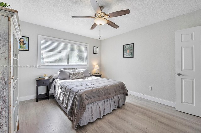 bedroom with baseboards, a ceiling fan, light wood-style floors, and a textured ceiling