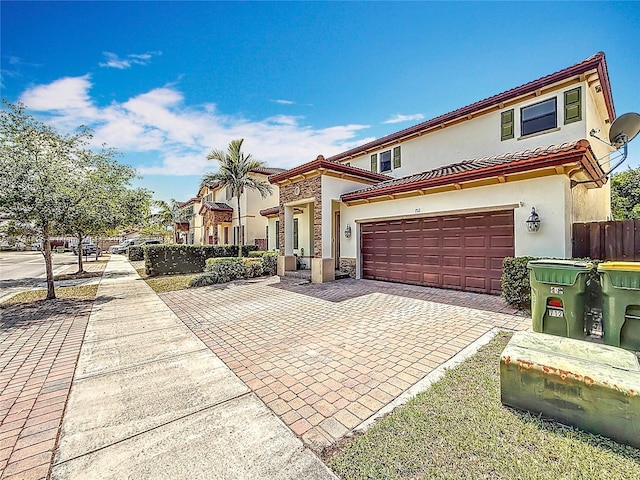 mediterranean / spanish-style home with stucco siding, decorative driveway, an attached garage, a tile roof, and fence