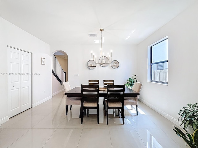 dining area featuring light tile patterned floors, baseboards, visible vents, arched walkways, and an inviting chandelier