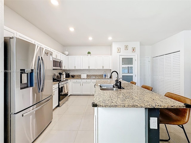 kitchen with a sink, a kitchen bar, stainless steel appliances, decorative backsplash, and light tile patterned flooring