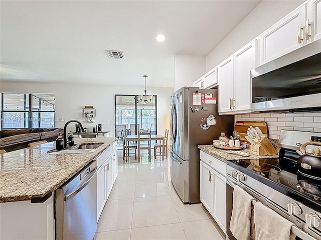 kitchen featuring tasteful backsplash, light tile patterned floors, visible vents, stainless steel appliances, and a sink