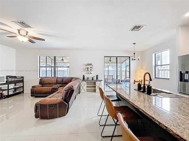 living area featuring a textured ceiling, light tile patterned floors, a ceiling fan, and visible vents