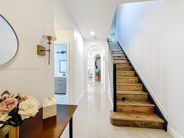 interior space with visible vents, baseboards, arched walkways, and tile patterned flooring