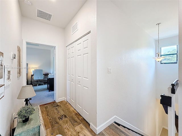 corridor with visible vents, baseboards, and wood finished floors