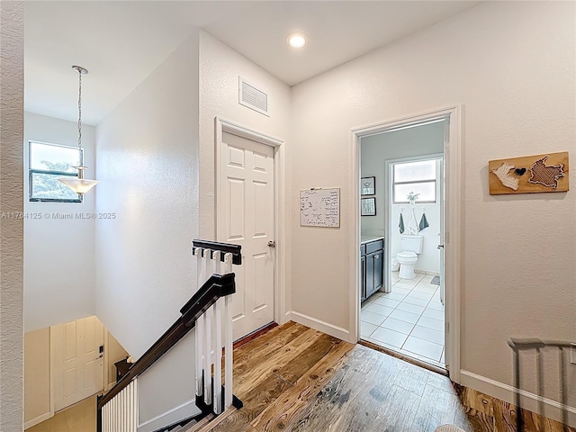 foyer entrance with visible vents, baseboards, light wood finished floors, and a healthy amount of sunlight