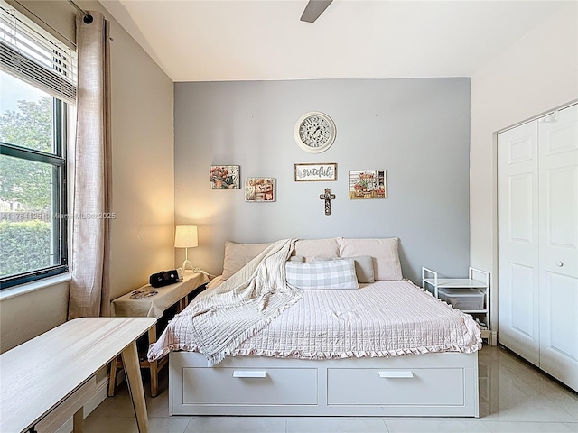 bedroom with a closet, light tile patterned floors, multiple windows, and ceiling fan