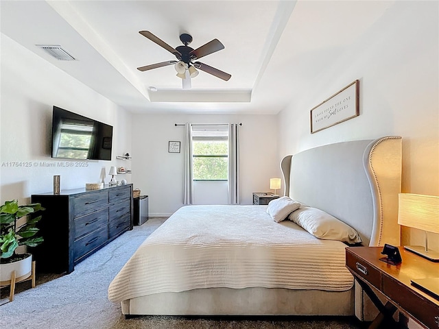 bedroom featuring ceiling fan, visible vents, light carpet, a raised ceiling, and baseboards