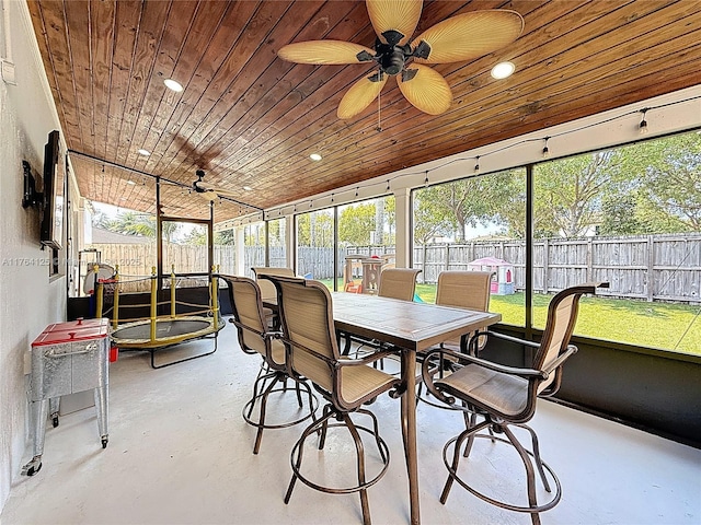 sunroom featuring wood ceiling, concrete floors, ceiling fan, and outdoor dining area