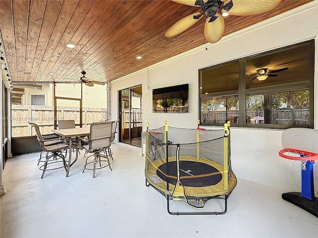 sunroom / solarium with wooden ceiling, concrete floors, outdoor dining area, and ceiling fan