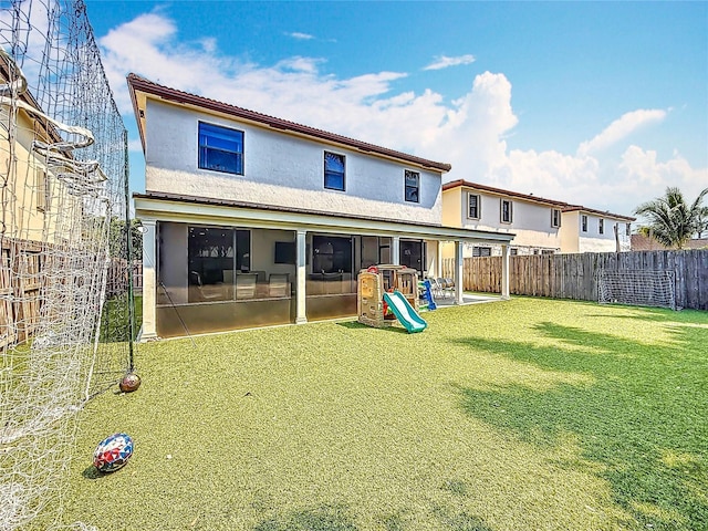 rear view of house featuring a fenced backyard, stucco siding, and a lawn