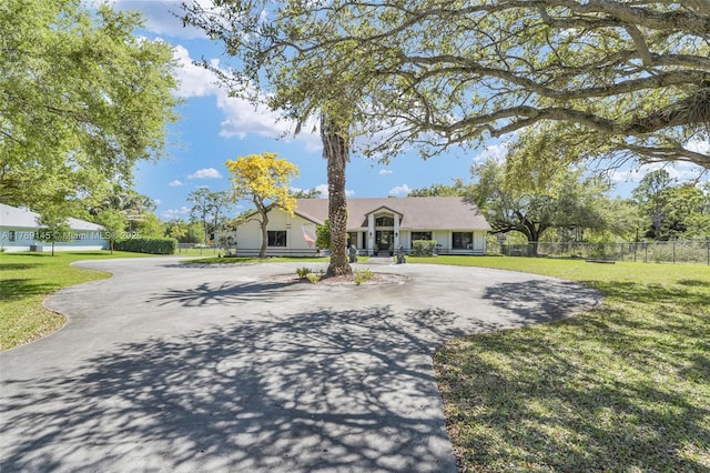 view of front facade featuring fence, a front lawn, and curved driveway