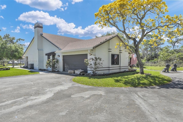 view of side of property featuring fence, a lawn, driveway, and a garage