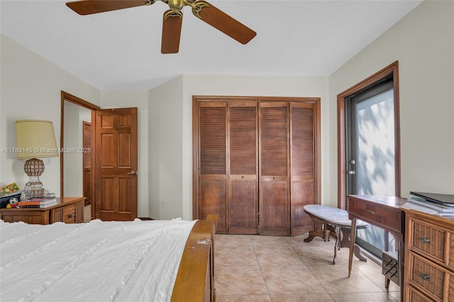 bedroom featuring a textured ceiling, a closet, ceiling fan, and light tile patterned floors