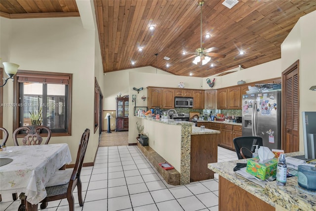 kitchen featuring lofted ceiling, wood ceiling, light tile patterned flooring, appliances with stainless steel finishes, and brown cabinetry