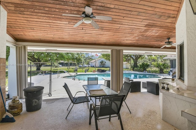 view of patio / terrace featuring glass enclosure, ceiling fan, and an outdoor pool