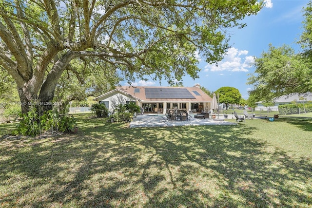 back of house featuring a lawn, solar panels, and a patio