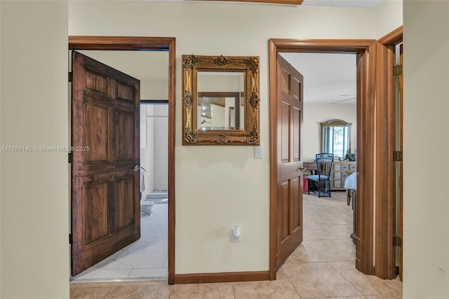 corridor featuring light tile patterned floors and baseboards