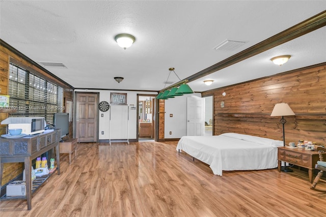 bedroom featuring visible vents, wood finished floors, wood walls, and a textured ceiling