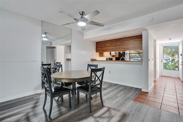 dining area with baseboards, a ceiling fan, a textured ceiling, and wood finished floors
