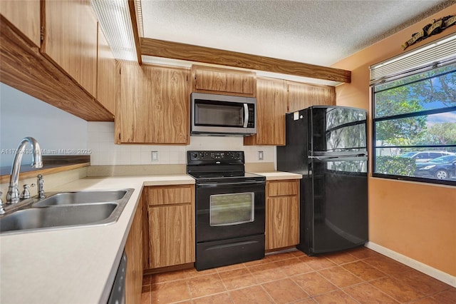 kitchen featuring light tile patterned flooring, a sink, light countertops, backsplash, and black appliances