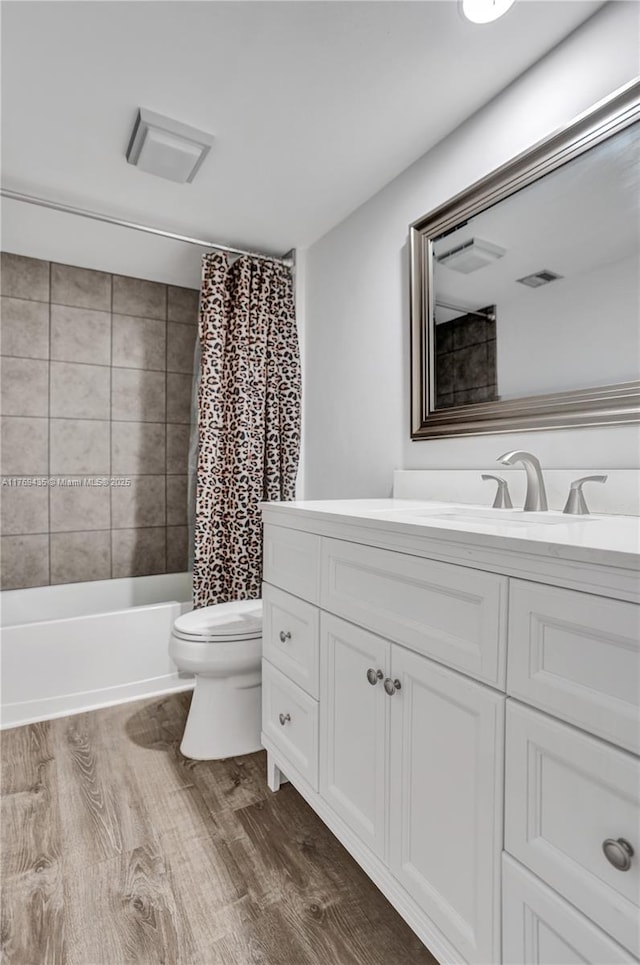 bathroom featuring vanity, toilet, wood finished floors, and shower / tub combo with curtain