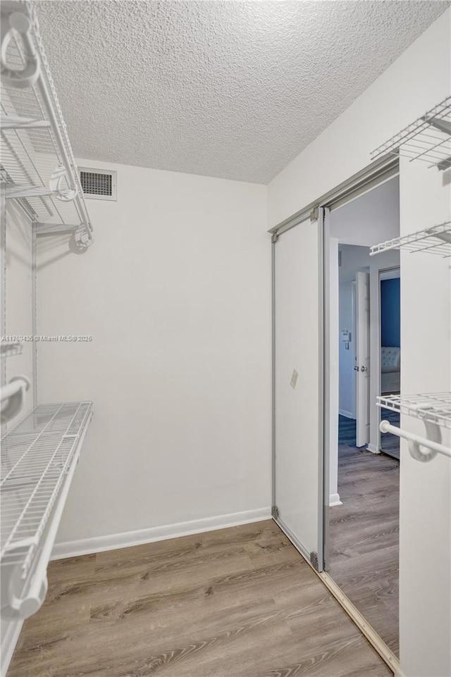 spacious closet featuring wood finished floors and visible vents