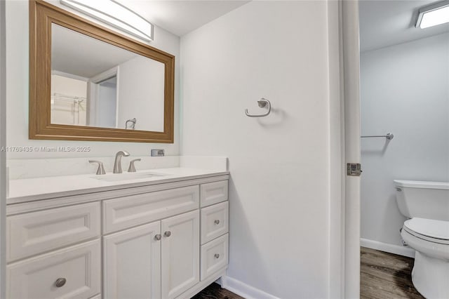 bathroom featuring baseboards, vanity, toilet, and wood finished floors