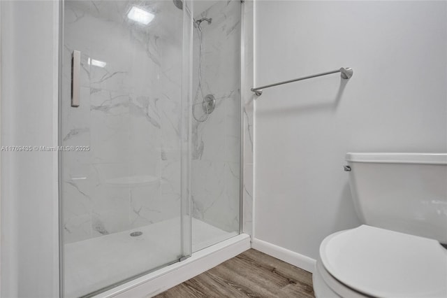 bathroom with toilet, baseboards, a marble finish shower, and wood finished floors