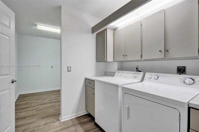 3515 Village Blvd Unit 105, West Palm Beach, FL 33409 - washroom with separate washer and dryer, baseboards, light wood-type flooring, and cabinet space