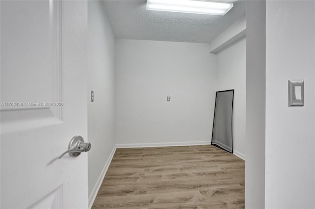 clothes washing area featuring baseboards, a textured ceiling, and wood finished floors