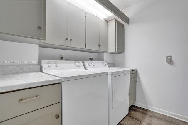 washroom featuring baseboards, cabinet space, wood finished floors, and washing machine and clothes dryer