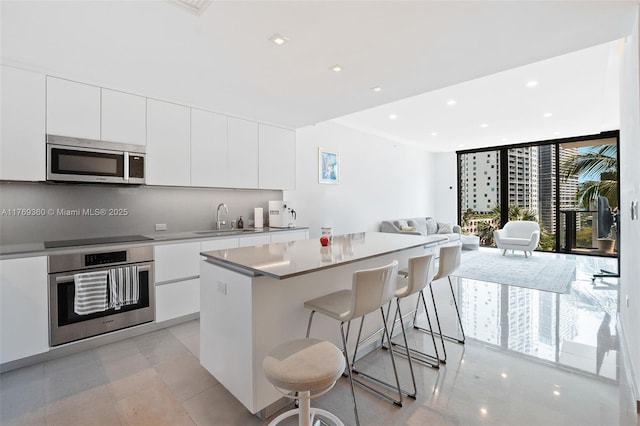 68 SE 6th St Unit 805, Miami, FL 33131 - kitchen with a sink, a kitchen island, white cabinetry, appliances with stainless steel finishes, and modern cabinets