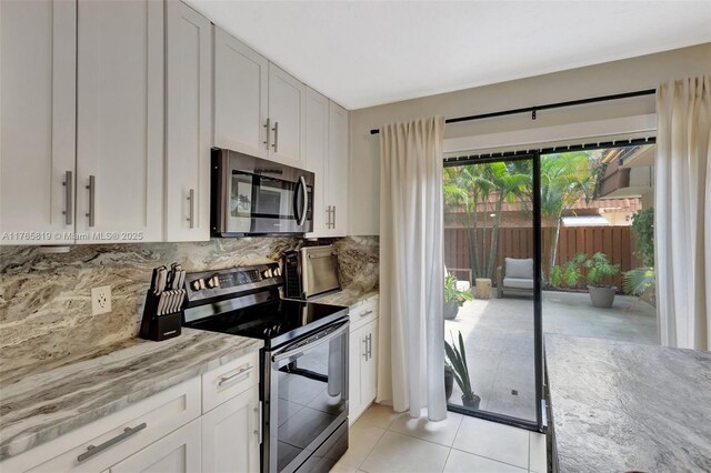 kitchen featuring light stone counters, decorative backsplash, stainless steel appliances, white cabinets, and light tile patterned flooring